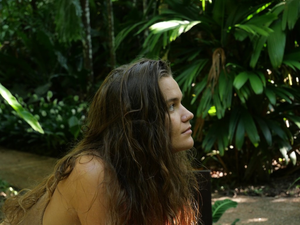 Close-up of a woman with a deep, focused gaze surrounded by nature