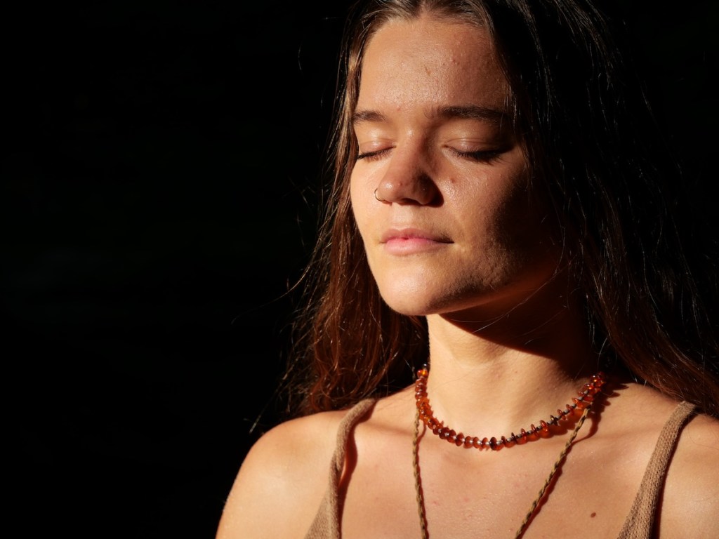 Close-up of woman with soft expression, focusing inward in a natural setting