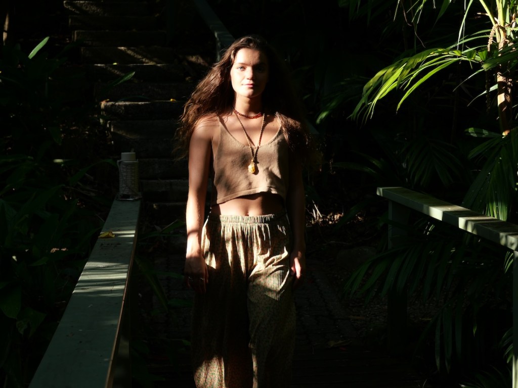 Woman walking through forest vegetation, moving forward among plants
