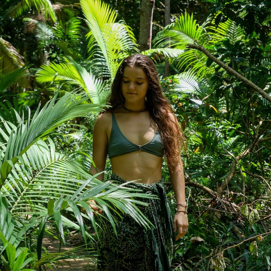 Woman immersed in dense forest vegetation, surrounded by greenery
