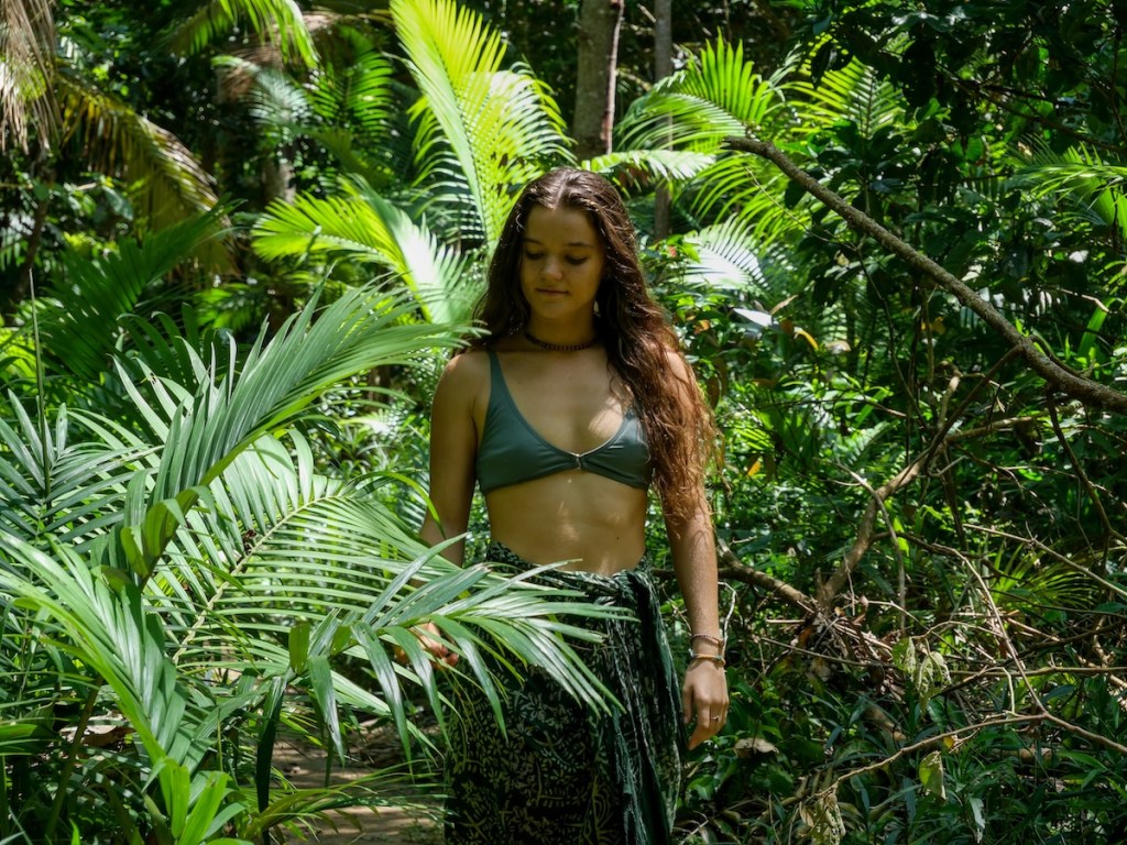 Woman immersed in dense forest vegetation, surrounded by greenery