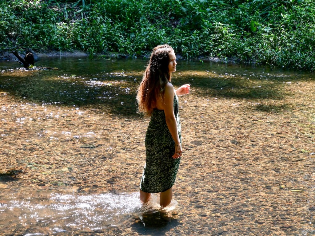Woman walking through shallow water in a natural forest environment