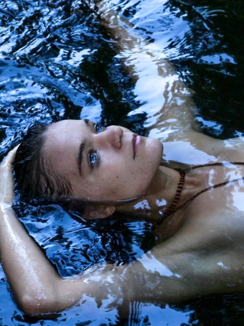 Woman floating peacefully in water, immersed in nature, symbol of connection and belonging