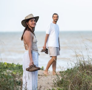 Cristina looks towards the camera while Matteo walks behind her at Yorkeys Knob Beach, Queensland, Australia.