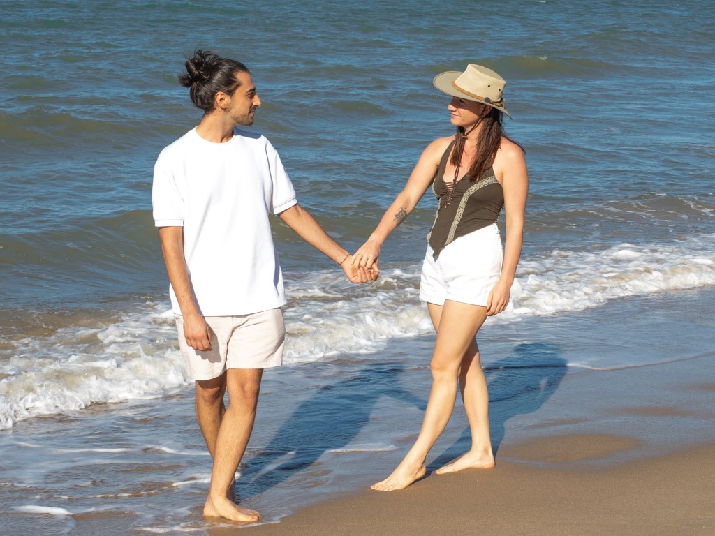 Cristina and Matteo holding hands while walking along Yorkeys Knob Beach, Queensland, Australia.